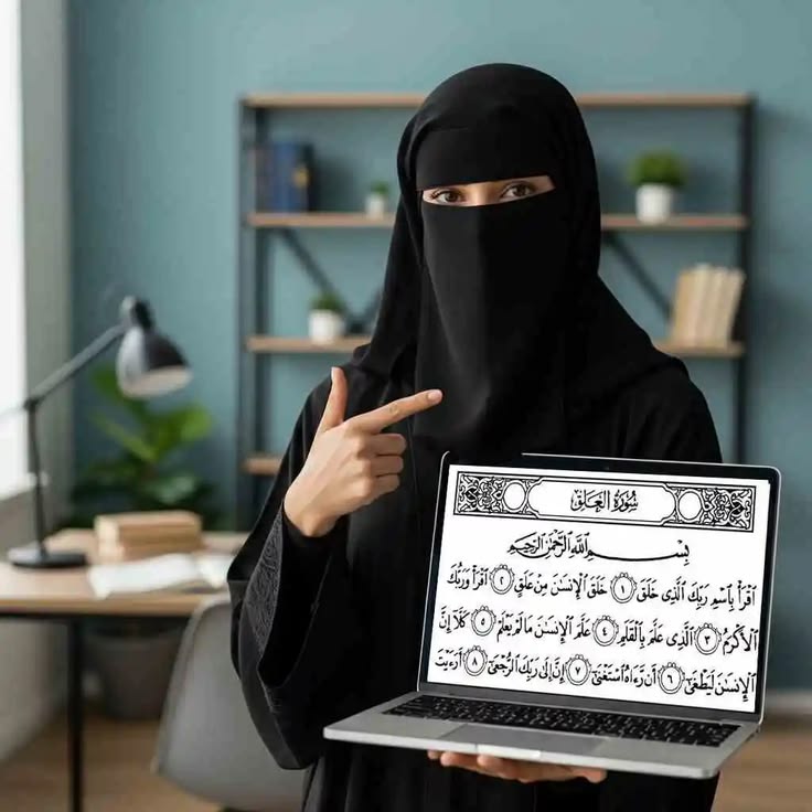 What Makes a Good Online Hifz Teacher A woman wearing a black niqab and abaya stands in a study room, pointing her finger toward a laptop screen displaying the Arabic text of Surah Al-Alaq from the Quran.